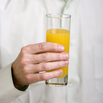 High glass with orange juice in a man's hand