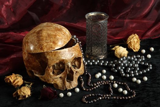 Skull of the person on a black background with pearls and dry colours