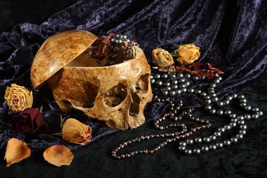 Skull of the person on a black background with pearls and dry colours