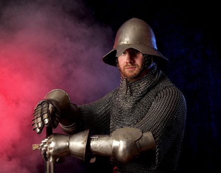 The soldier in a medieval knightly armour with we throw in hands