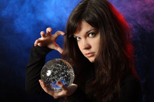 The beautiful girl with a crystal sphere, the sorcerer, against a dark background