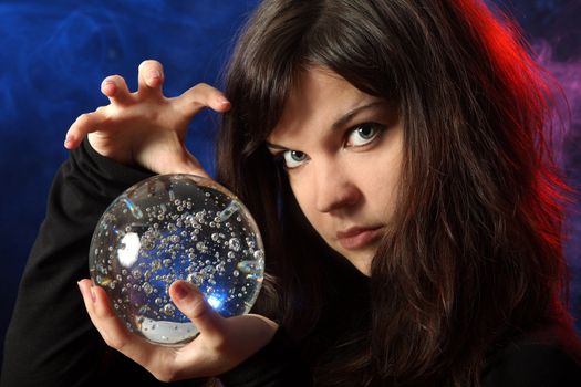 The beautiful girl with a crystal sphere, the sorcerer, against a dark background