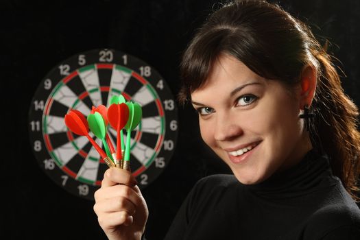 The beautiful girl with darts on a black background