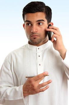 Ethnic mixed race businessman wearing traditional robe is using a mobile phone and looking sideways.