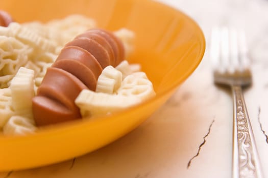Sausage and macaroni on plate and plug