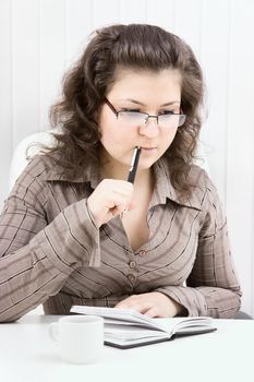 The young woman with notebook sits at table at office