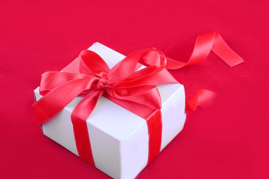 Giftbox with red ribbon on red background