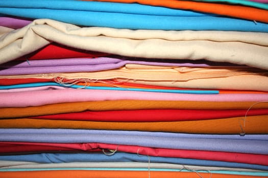 A background of a stack of fabrics in different colors.