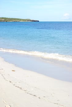 A warm tropical beach with the surf washing up on the white sands.