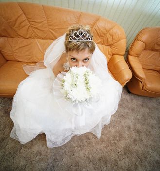 Bride sits on a brown leathern sofa