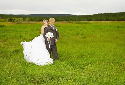 The bride and groom on nature in a green field