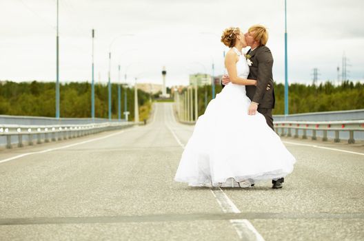 Newlyweds kissing passionately while standing on the highway