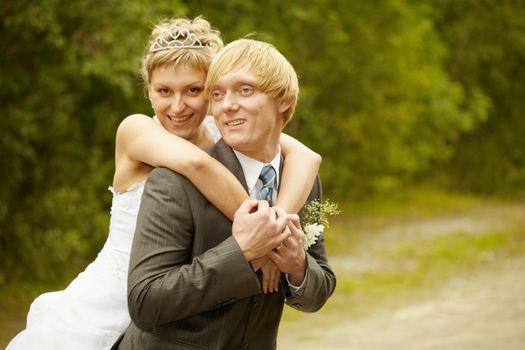 Happy young bride and groom hugging outdoors