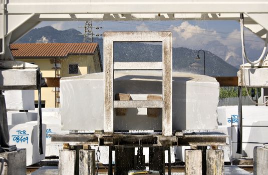 A cutting machine working a block of white marble, Tuscany, Italy