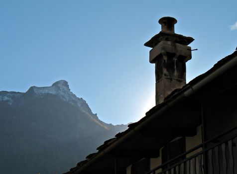 a chimney of an old country house, mountains in background