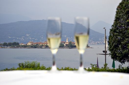 Two glasses of white wine in a restaurant on the lake Maggiore shore, Italy; focus on island