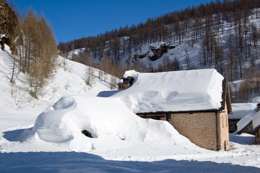 alpine house in a snowy winter landscape; Alpe Devero, Alps, Italy