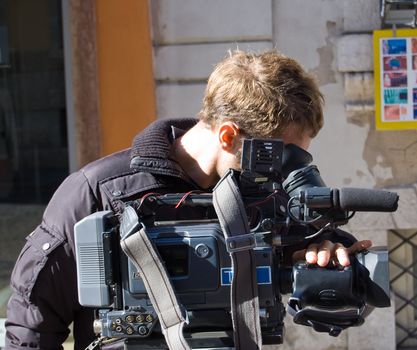 A cameraman is shooting a urban scene in a city center