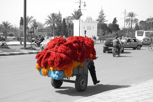 A man is drawing a barrow full of dyed wool, Marrakesh center