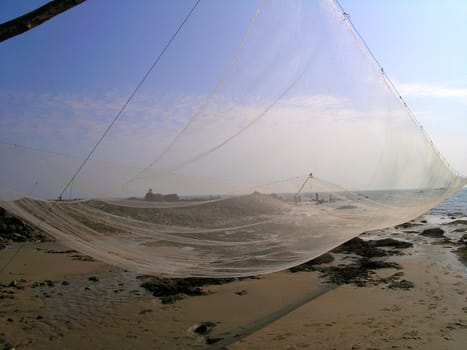 fishing net spread near the seashore against a sky