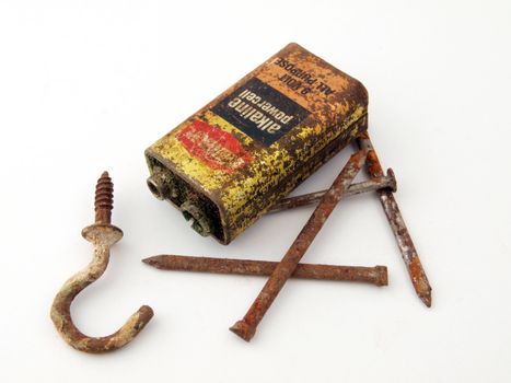 Rusty battery with nails and a hook.