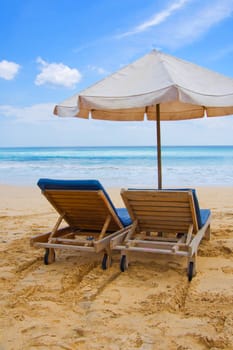 Sun, umbrella and chairs on sandy beach in Bali, Indonesia.