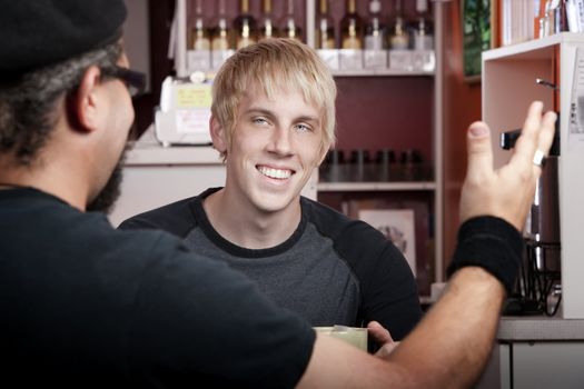 Cheerful young blonde man reacting to coffee house conversation