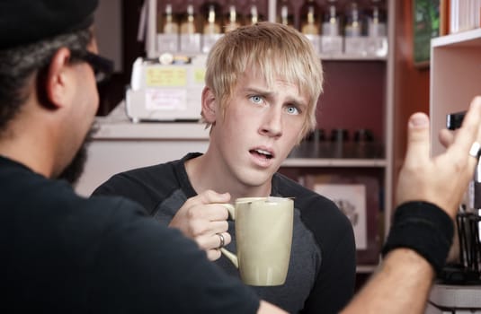 Shocked young blonde man reacting to coffee house conversation