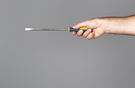 An image of a screwdriver with hand over grey background