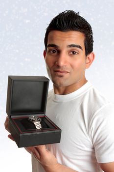 An adult man showing  or holding up a watch or other product in a box.  