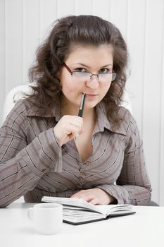 The young woman with notebook sits at table at office