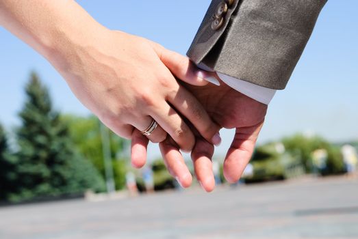 groom's hand holding bride's hand with a wedding bands