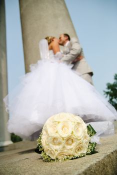 bridal bouquet of white roses and blurred newlyweds at background