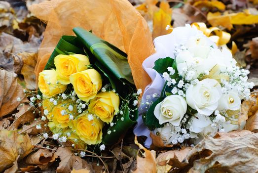 two bridal bouquet of white and yellow roses on an autumn leaves