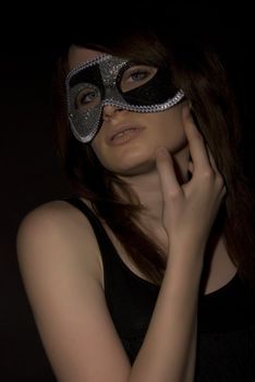 Portrait of a young brunette in mask over black