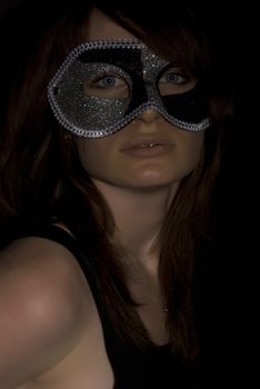 Portrait of a young brunette in mask over black