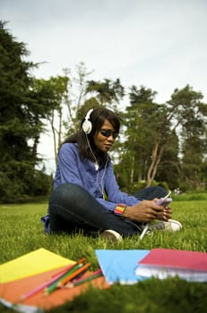 Black woman listening to the music in a park with white headphones