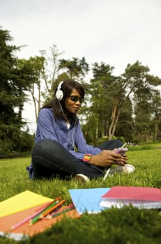 Black woman listening to the music in a park with white headphones