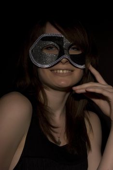 Portrait of a young brunette in mask over black