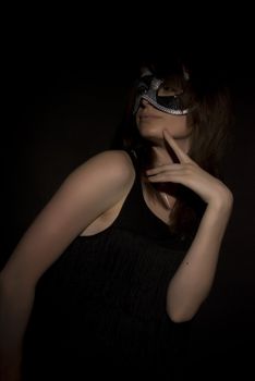 Portrait of a young brunette in mask over black