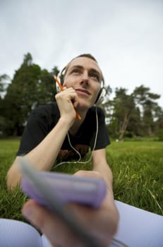 Man listening to the music in a park with white headphones