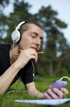 Man listening to the music in a park with white headphones