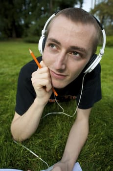 Man listening to the music in a park with white headphones