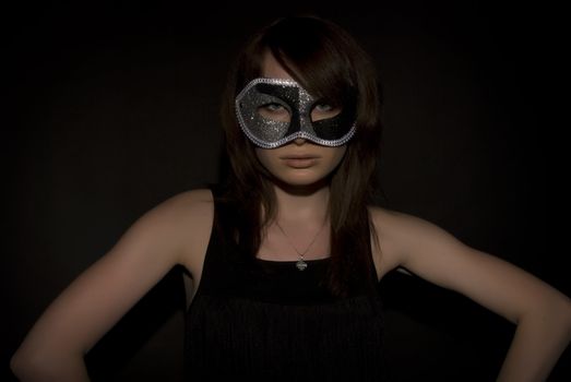 Portrait of a young brunette in mask over black