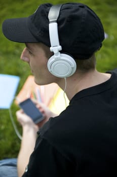 Man listening to the music in a park with white headphones