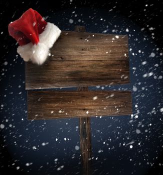 Weathered wooden sign with santa hat on snowy background