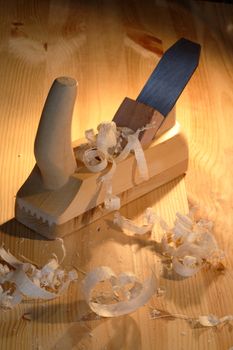 Old wood planer and shavings on wooden background