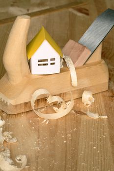 Paper house standing on wood planer on wooden background