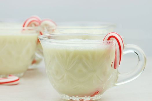 Delicious eggnog with mini candy canes. Shallow DOF with selective focus on cup in foreground.