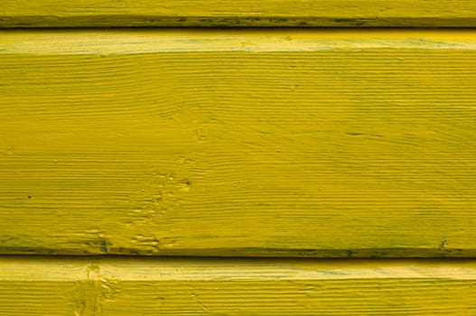 Structure of a fragment of a wall from boards painted with a yellow paint.